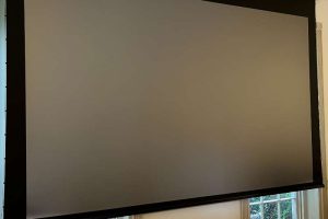 Close-up of a projector screen lowered in a conference room setup.