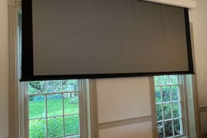 Close-up of a projector screen lowered in a conference room setup.