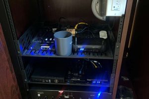 Close-up of an audio-visual equipment rack with cables and connected devices in a cabinet.