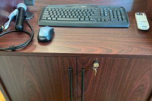 Podium with a keyboard, mouse, and microphone setup for presentations, featuring a wooden finish.